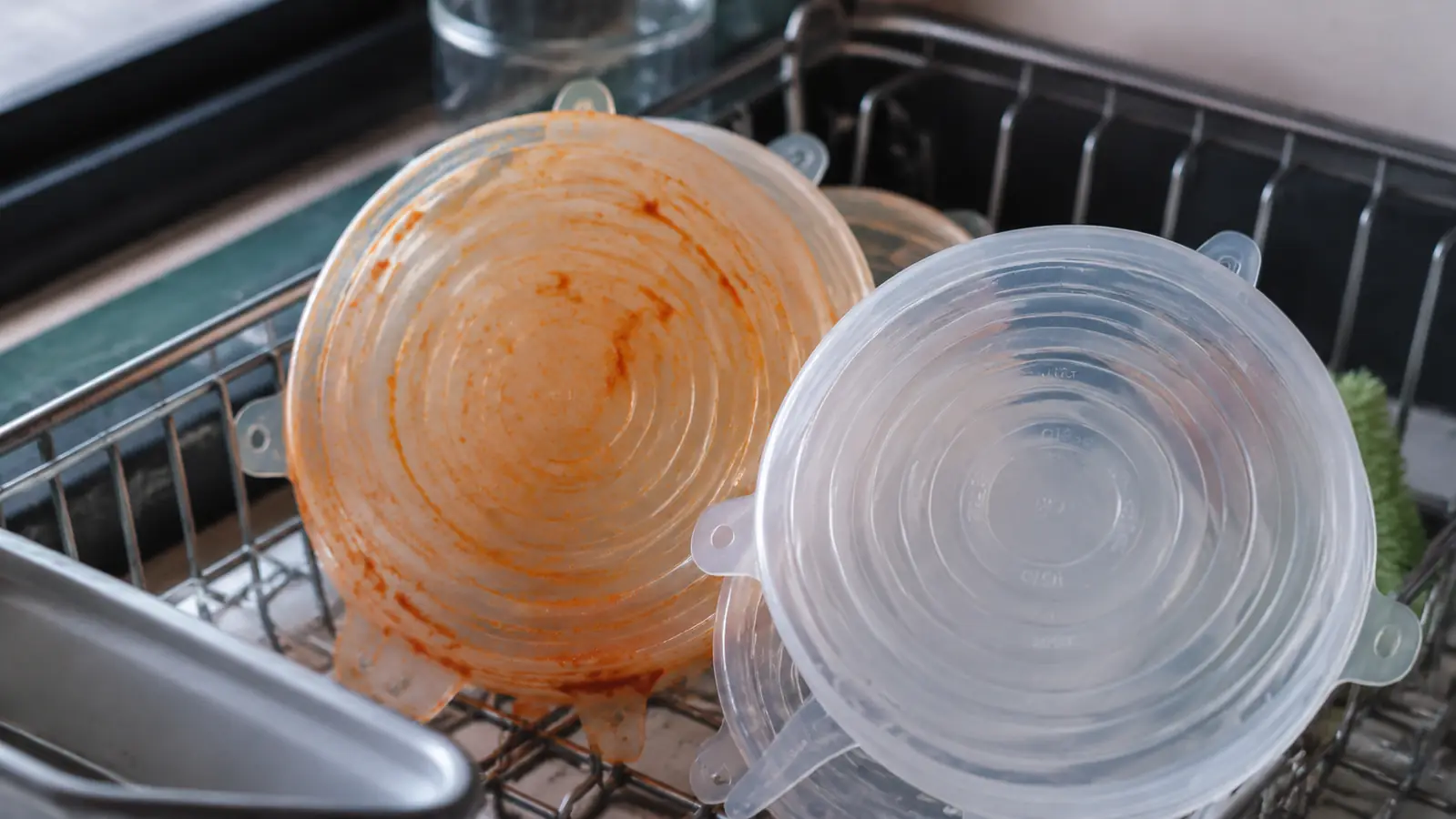 A stack of stained and clean silicone lids side by side on a drying rack