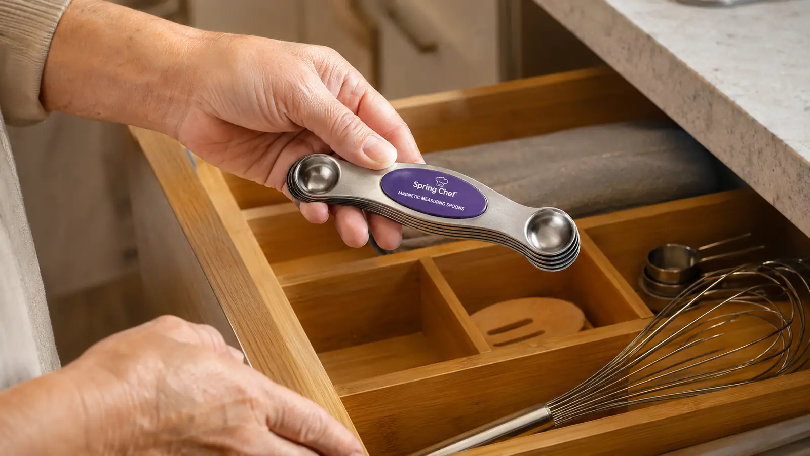 Hand holding a stack of magnetic measuring spoons snapped together in a flat stack