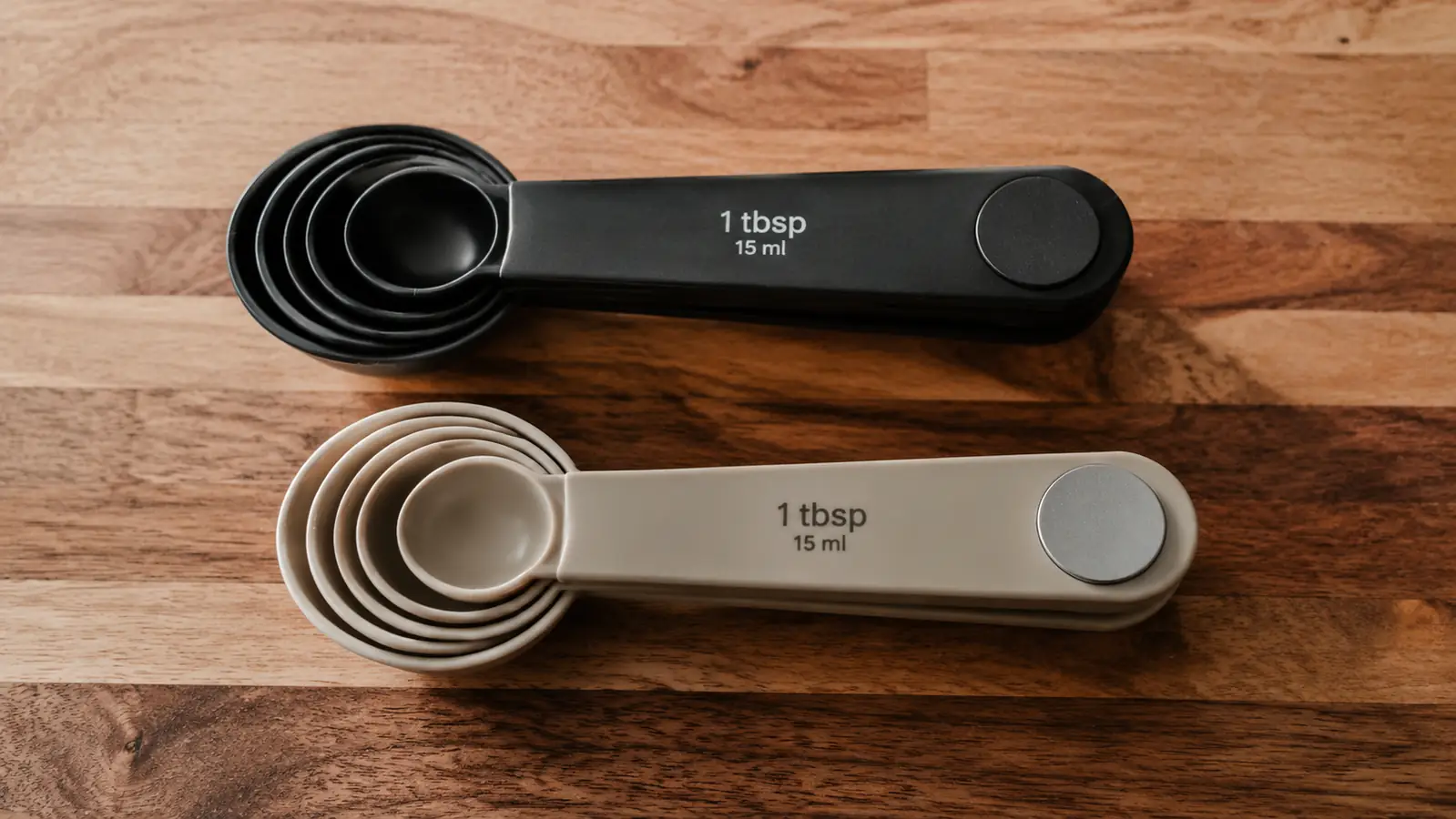 Two sets of magnetic measuring spoons stacked side by side on a kitchen counter, one labeled Spring Chef and one labeled BIDFUL